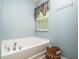 Bathroom with soaking tub, light blue walls, and a window at 1209 Partington St, Wake Forest, NC 27587