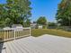 Spacious backyard featuring a white deck, green lawn, and mature trees on a sunny day at 1230 Piney Glen Ln, Zebulon, NC 27597