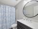 Bathroom featuring white sink and vanity, round mirror, and a tub with a blue floral shower curtain at 1230 Piney Glen Ln, Zebulon, NC 27597
