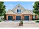 Three-car garage with brick facade and yellow siding, enhances curb appeal with charming landscaping at 127 Bobwhite Way, Mebane, NC 27302