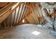 Unfinished attic space featuring exposed wooden beams, unfinished flooring, and a small window at 1409 Montvale Ridge Dr, Cary, NC 27519