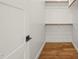 Walk-in closet with hardwood floors, a door with a black handle, and wood shelving at 1409 Montvale Ridge Dr, Cary, NC 27519