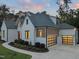 Rear elevation of a modern home with elegant garage doors, white siding and brick, completed by mature landscaping at 1409 Montvale Ridge Dr, Cary, NC 27519