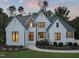 Elegant two-story home with white brick, complemented by black windows, and a meticulously landscaped front yard at dusk at 1409 Montvale Ridge Dr, Cary, NC 27519