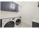 Well-equipped laundry room with a side-by-side washer and dryer, stylish cabinets, and a patterned tile floor at 1409 Montvale Ridge Dr, Cary, NC 27519