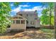 Back exterior view of the home with a screened-in porch, mature trees, and a wooden fence at 1905 Indianwood Ct, Raleigh, NC 27604