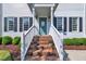 Inviting front entrance with brick steps, white railings, and a charming teal front door, surrounded by manicured landscaping at 1905 Indianwood Ct, Raleigh, NC 27604