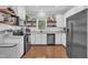 Well-lit kitchen with stainless steel appliances, white cabinets, and floating wooden shelves at 1905 Indianwood Ct, Raleigh, NC 27604