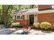 Inviting entrance of brick home featuring a black front door, decorative bushes, and walkway at 2005 Cole Mill Rd, Durham, NC 27712
