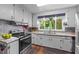 Bright kitchen features stainless steel appliances, white cabinets, and a view of the backyard at 2005 Cole Mill Rd, Durham, NC 27712