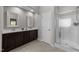 Bathroom featuring double sinks with dark wood cabinetry and a tiled shower with glass door at 2057 Tanners Mill Dr, Durham, NC 27703
