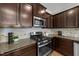 A well-equipped kitchen features granite countertops, stainless appliances, and dark wood cabinets at 2057 Tanners Mill Dr, Durham, NC 27703
