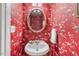 Charming powder room featuring vibrant wallpaper, a pedestal sink, and decorative mirror at 206 W Stoneybrook Ct, Benson, NC 27504