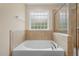 Bright bathroom features a soaking tub under a window and a separate glass-enclosed shower at 210 Strolling Way, Durham, NC 27707