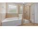 Bright bathroom features a soaking tub under a window and a separate glass-enclosed shower at 210 Strolling Way, Durham, NC 27707