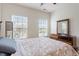 Bright bedroom with two windows letting in natural light, complemented by a wooden dresser with a mirror at 2122 Aventon Ln, Morrisville, NC 27560