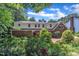 Home exterior with brick and white siding, surrounded by lush greenery and mature trees at 2204 Basil Drive, Raleigh, NC 27612