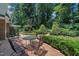 Landscaped backyard featuring mature trees, manicured shrubs, and a brick patio at 2204 Basil Drive, Raleigh, NC 27612