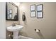 Powder room featuring a pedestal sink, mirror, and framed wall art for a unique and stylish design at 228 Grantwood Dr, Holly Springs, NC 27540