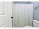Bright bathroom featuring a shower with a patterned curtain and white toilet and blue painted walls at 228 Grantwood Dr, Holly Springs, NC 27540