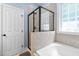 Well-lit bathroom with a glass-enclosed shower, soaking tub, and neutral tile work providing a spa-like experience at 228 Grantwood Dr, Holly Springs, NC 27540