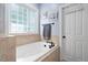 Relaxing bathroom featuring a soaking tub with stone surround, a window, and a door, creating a private retreat at 228 Grantwood Dr, Holly Springs, NC 27540