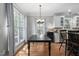 Dining area with hardwood floors, black dining table, and kitchen view, bathed in natural light at 228 Grantwood Dr, Holly Springs, NC 27540