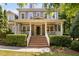 Inviting two-story home boasts a charming front porch, brick stairs and meticulously manicured landscaping at 228 Grantwood Dr, Holly Springs, NC 27540