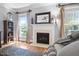 Cozy living room with a fireplace, hardwood floors, and large windows providing plenty of natural light at 228 Grantwood Dr, Holly Springs, NC 27540