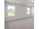 Bright bedroom with plush carpet and two windows overlooking a green lawn at 267 Old Fashioned Way, Lillington, NC 27546