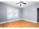 A light and airy empty room with gray walls, hardwood floors, a ceiling fan, and a large window at 307 W Austin St, Mebane, NC 27302