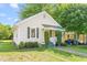 Charming bungalow featuring a green metal roof, a covered porch with white railings, and trimmed front shrubs at 307 W Austin St, Mebane, NC 27302