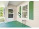 Well-lit front porch with a dark-green painted floor, a storm door, and a small decorative side table at 307 W Austin St, Mebane, NC 27302