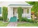 Charming front porch with green steps, a white railing, an outdoor wreath, and manicured bushes at 307 W Austin St, Mebane, NC 27302