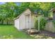 Charming white backyard storage shed with a small porch, surrounded by lush greenery at 307 W Austin St, Mebane, NC 27302