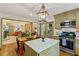 Bright kitchen with adjacent living room, island with marble countertop, stainless steel appliances, and olive-green cabinetry at 3308 Cobblestone Court Ct, Raleigh, NC 27607