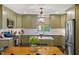 Charming kitchen with olive green cabinetry, stainless steel appliances, island with marble countertop, and hardwood floors at 3308 Cobblestone Court Ct, Raleigh, NC 27607