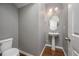 Charming powder room with pedestal sink, decorative wallpaper, and wood floors at 337 Botan Way, Hillsborough, NC 27278