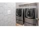 Updated laundry room with gray patterned wallpaper and modern washer and dryer units at 337 Botan Way, Hillsborough, NC 27278