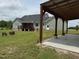 View of the backyard with a covered patio, and firepit with chairs on a well-maintained lawn at 540 Pine Ridge Rd, Zebulon, NC 27597