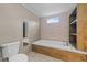 Relaxing bathroom featuring a luxurious soaking tub, wood paneled accents, and a bright window at 540 Pine Ridge Rd, Zebulon, NC 27597