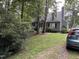 View of the home's exterior showcasing mature trees, green grass, and driveway at 5816 Henner Pl, Durham, NC 27713