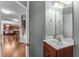Powder room with a cherry wood vanity and white sink; view into adjacent living area at 712 Brittley Way, Apex, NC 27502