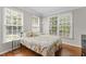 Cozy bedroom with three windows offering lots of natural light and hardwood floors at 712 Brittley Way, Apex, NC 27502