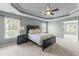 Primary bedroom with tray ceilings, a ceiling fan, and two windows, plus an attached room at 712 Brittley Way, Apex, NC 27502