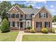 Charming two-story brick home featuring a landscaped yard, black shutters, and a welcoming entrance at 712 Brittley Way, Apex, NC 27502