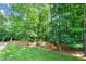 Secluded backyard features mature trees, a lush lawn, and a charming swing for peaceful relaxation at 7552 Hasentree Club Dr, Wake Forest, NC 27587