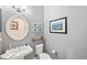 Cozy powder room with pedestal sink, decorative mirror, and charming wall art at 7552 Hasentree Club Dr, Wake Forest, NC 27587