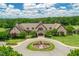 Aerial view of a grand exterior with a circular driveway, manicured landscaping, and a stone facade at 7552 Hasentree Club Dr, Wake Forest, NC 27587