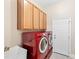 Bright laundry room features a red washer and dryer set, ample cabinet storage, and a utility sink at 7552 Hasentree Club Dr, Wake Forest, NC 27587
